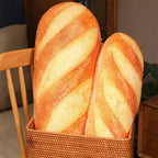 Two realistic baguette plush cushions placed in a woven basket, styled as playful home decor accents.