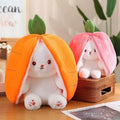 Two white bunny plush toys in carrot and strawberry hoods.