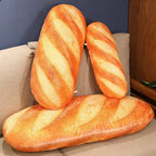 Three oversized realistic baguette plush pillows displayed on a couch, designed as soft novelty cushions for home decor and lounging.