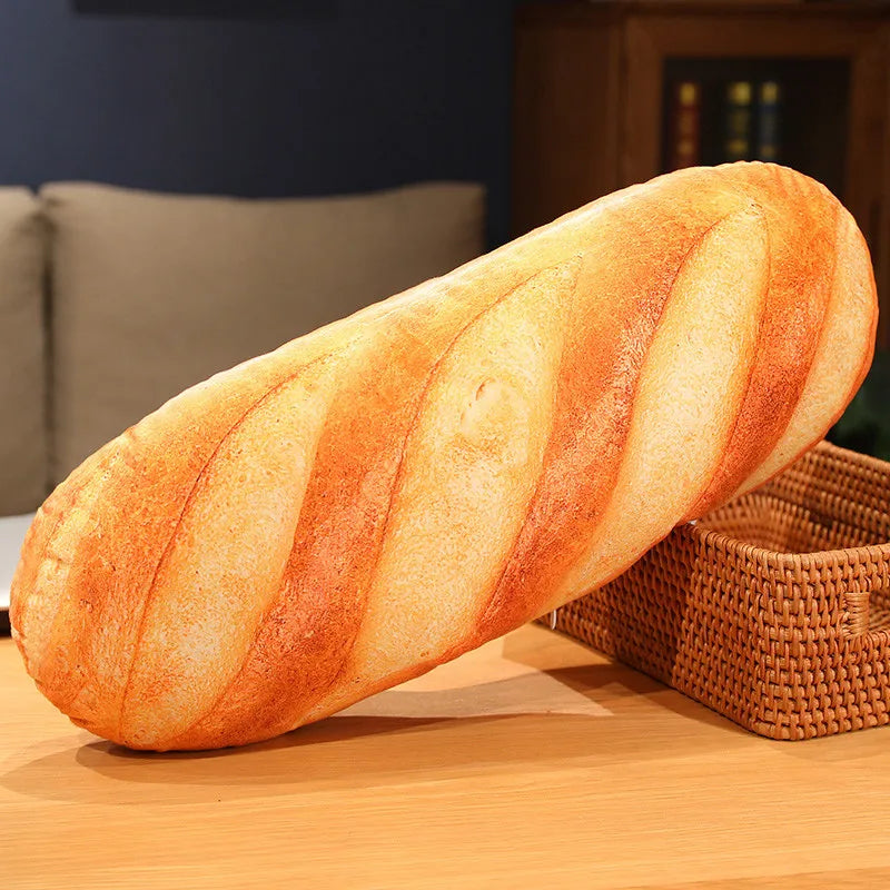 Single baguette plush pillow resting on a wooden surface, highlighting the detailed baked-bread design texture.