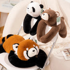 Three plush animal neck pillows shaped like a panda, brown bear, and red panda, draped over a white chair in a cozy indoor setting.