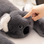 Cute koala stuffed animal with white ears and black nose, squished softly by a hand to highlight its plush comfort.