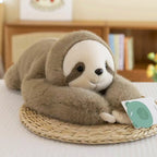Soft brown sloth plush toy with white face and dark eye patches, lying on a woven mat in a cozy indoor setting.