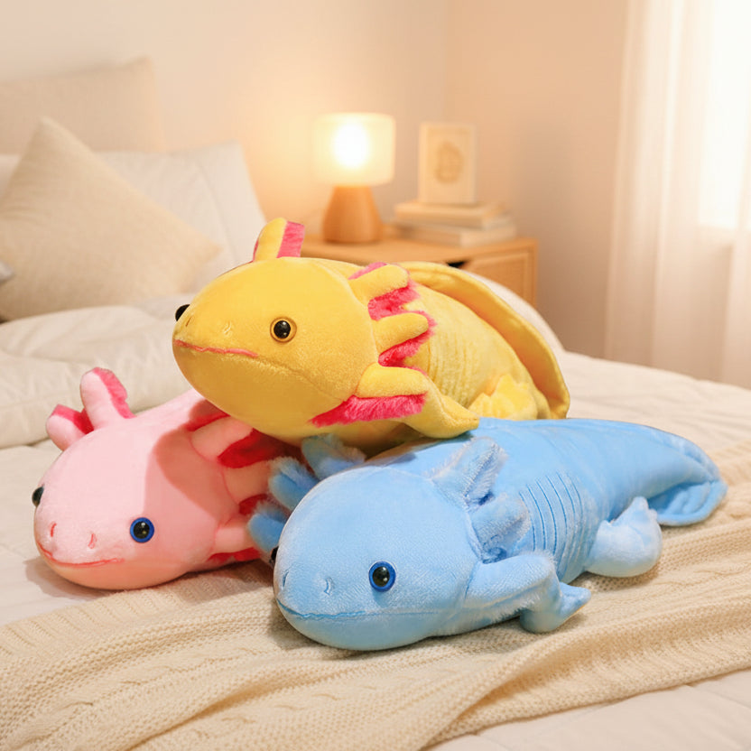 Sleepy Buddies Axolotls colorful plush toys in pink, blue and yellow resting on a cozy bed