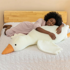Curly haired Black woman sleeping hugging giant white goose plush toy on bed for Sleepy Buddies