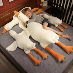 Young blond boy sleeping with multiple giant white goose plush toys on crib bed for Sleepy Buddies
