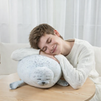 Young man peacefully resting on a sleepy-buddies sleeping seal plush happy pillow, soft stuffed animal cushion for relaxation and comfort