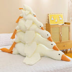 Stack of giant white goose plush toys on bed with yellow duck poster for Sleepy Buddies